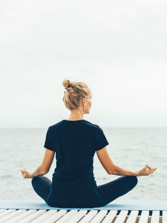 A women meditate calmly by the ocean